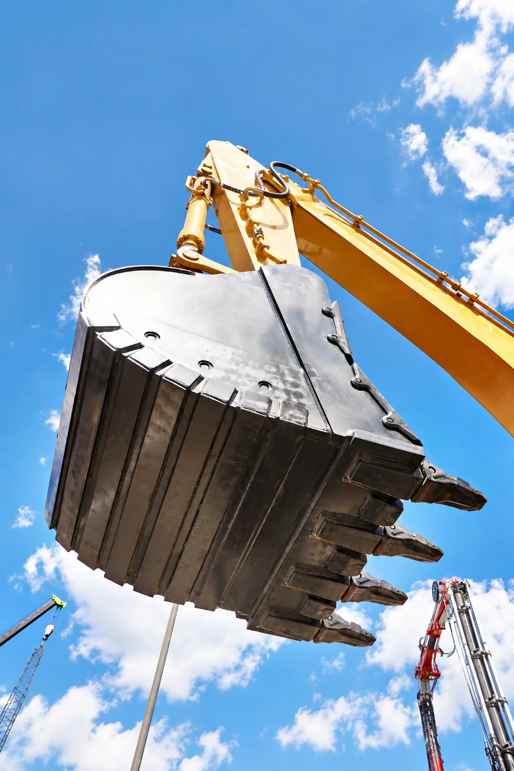 An excavator bucket raised against a blue sky